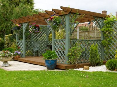 This is an image of a beautiful garden pergola with sitting area and table underneath.